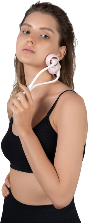 Three-quarter view of a young woman massaging her face with a face roller