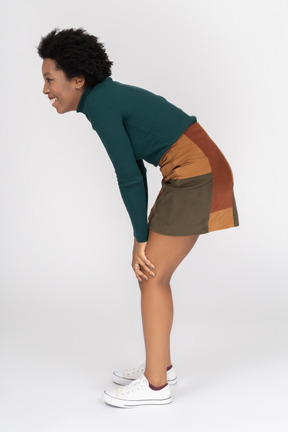 Side view of a woman standing and leaning on her knees