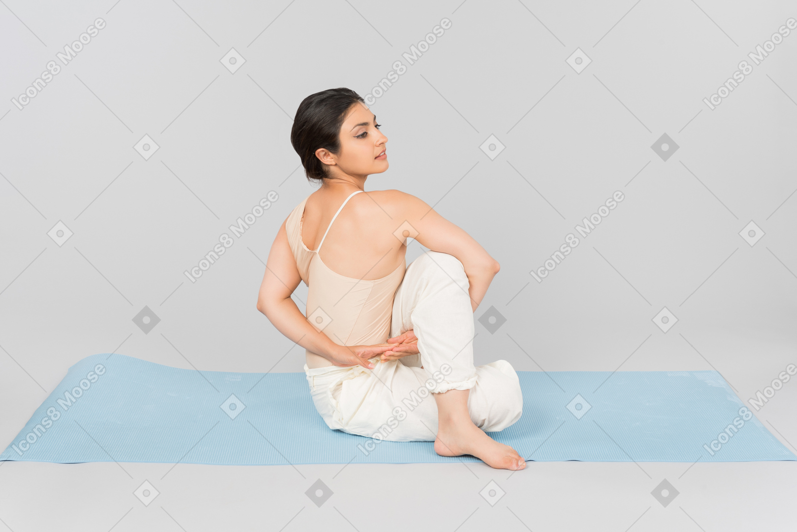 Junge indische frau, die auf yogamatte sitzt