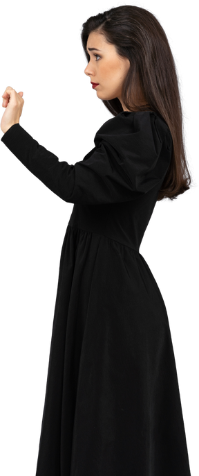 Seitenansicht einer jungen dame in einem schwarzen kleid, die ihre hand hebt