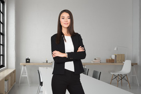 A business woman standing with her arms crossed in front of an empty office