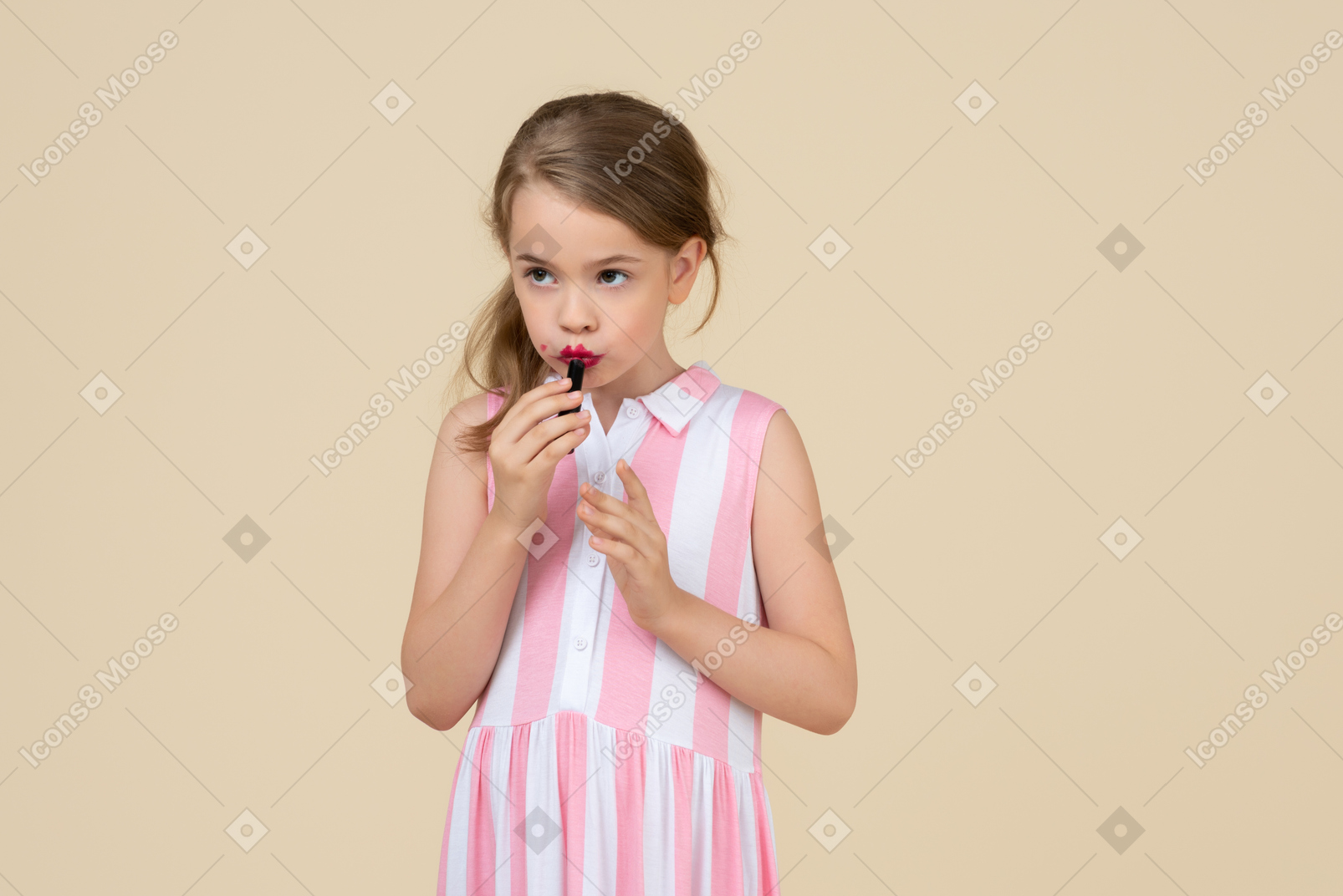 Cute little girl applying red lipstick