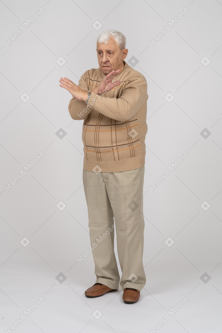 一位穿着休闲服的悲伤老人的正面图，显示停止手势