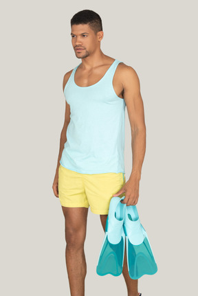 Man in yellow shorts holding swimming fins