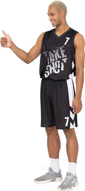 Vista di tre quarti di un giovane giocatore di basket maschile che mostra il pollice in su