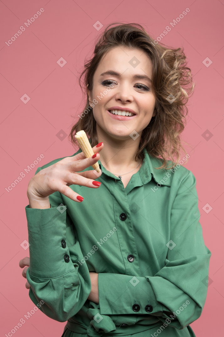 Mujer alegre imitando un cigarro fumando con un maíz baby