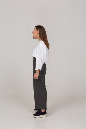 Side view of a screaming young lady in office clothing showing tongue