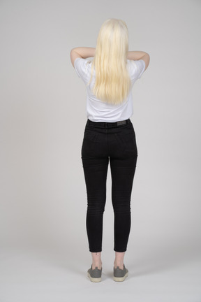 Vista traseira de uma mulher de cabelos compridos, pressionando as mãos na cabeça