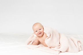 베이지 색 니트 담요로 덮여 웃는 아기