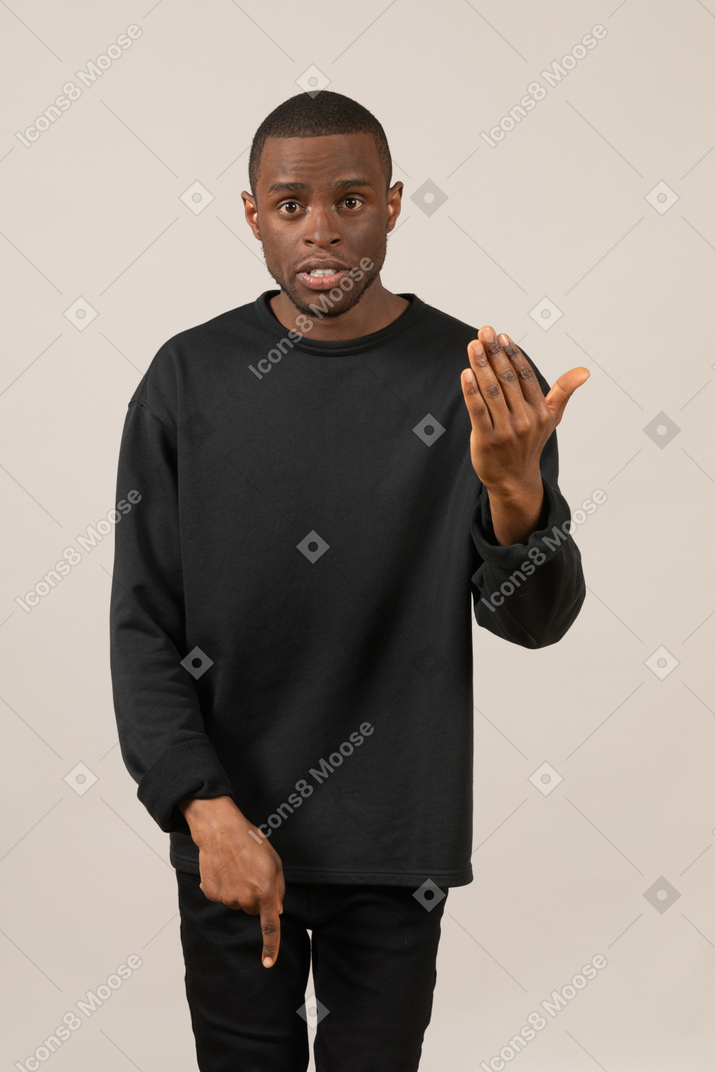 Man in black clothes looking at camera and pointing down