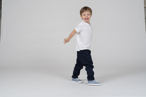 Vista lateral de um menino andando e mostrando a língua de brincadeira