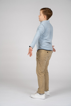 Vista laterale di un ragazzo in piedi con le braccia tese