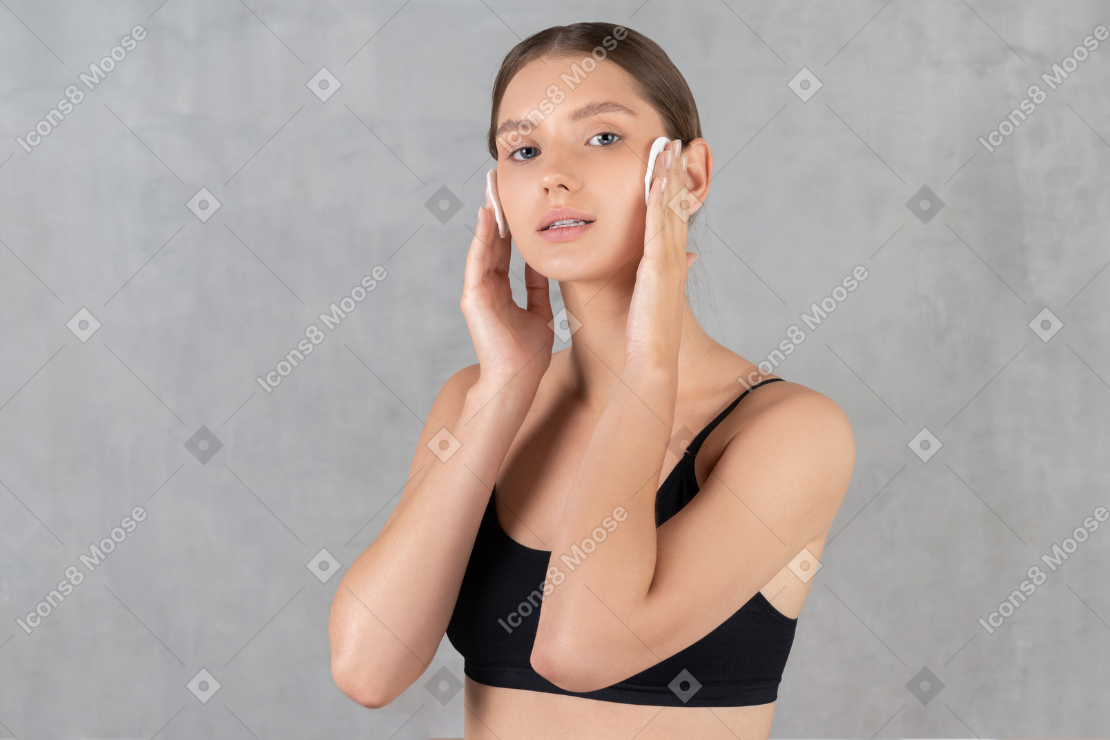 Young woman wiping her face with cotton pads
