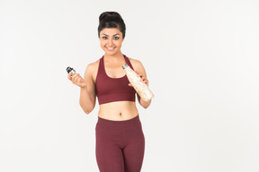 Jeune femme indienne sportswear tenant une bouteille de sport