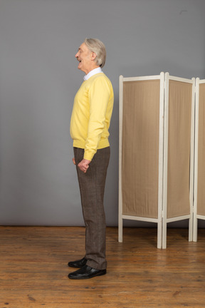 Side view of a screaming old man standing still