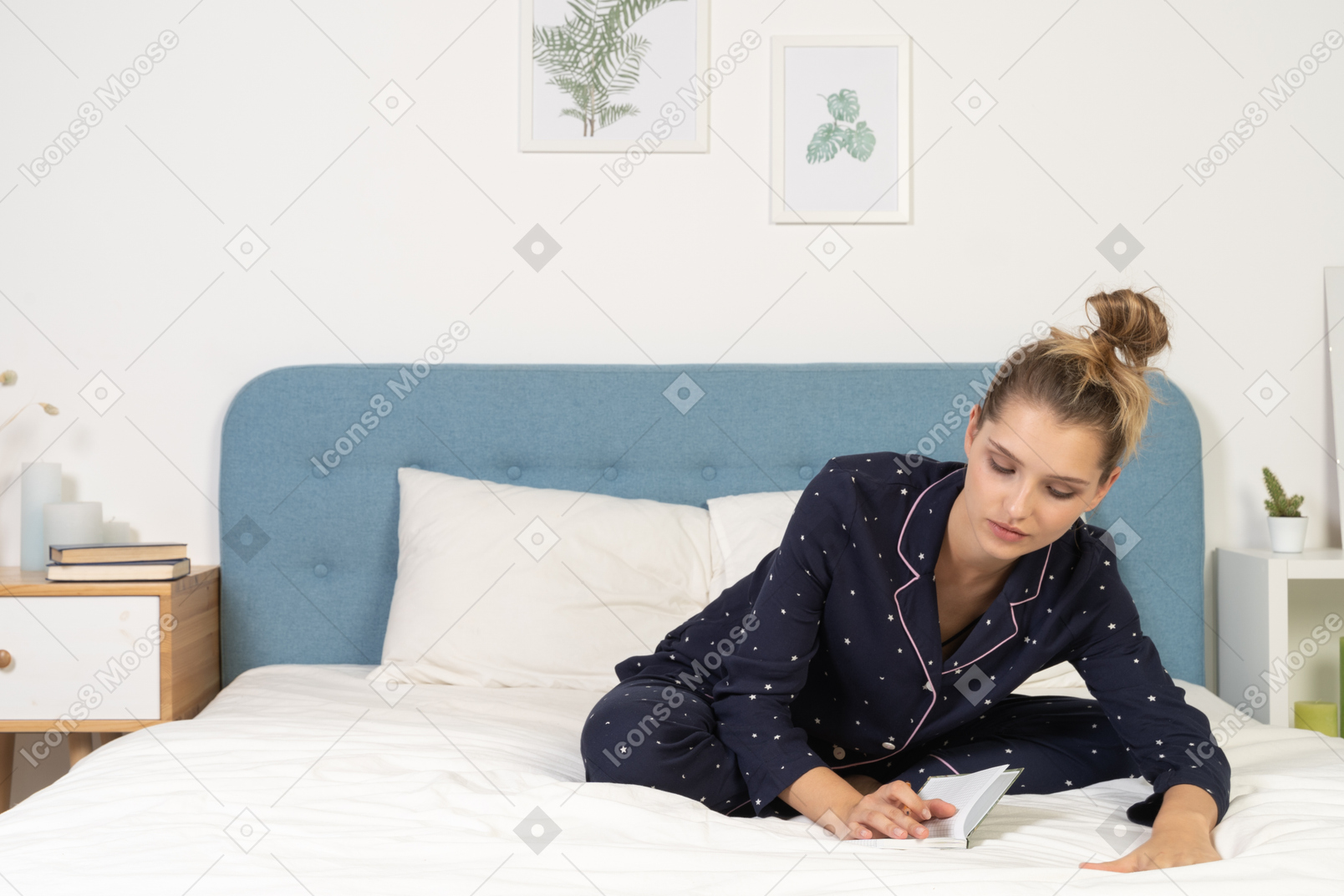 Front of a young female in pajama sitting in bed and making notes