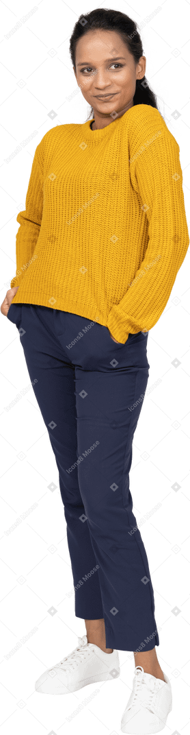 Front view of a happy girl in casual clothes posing with hands in pockets