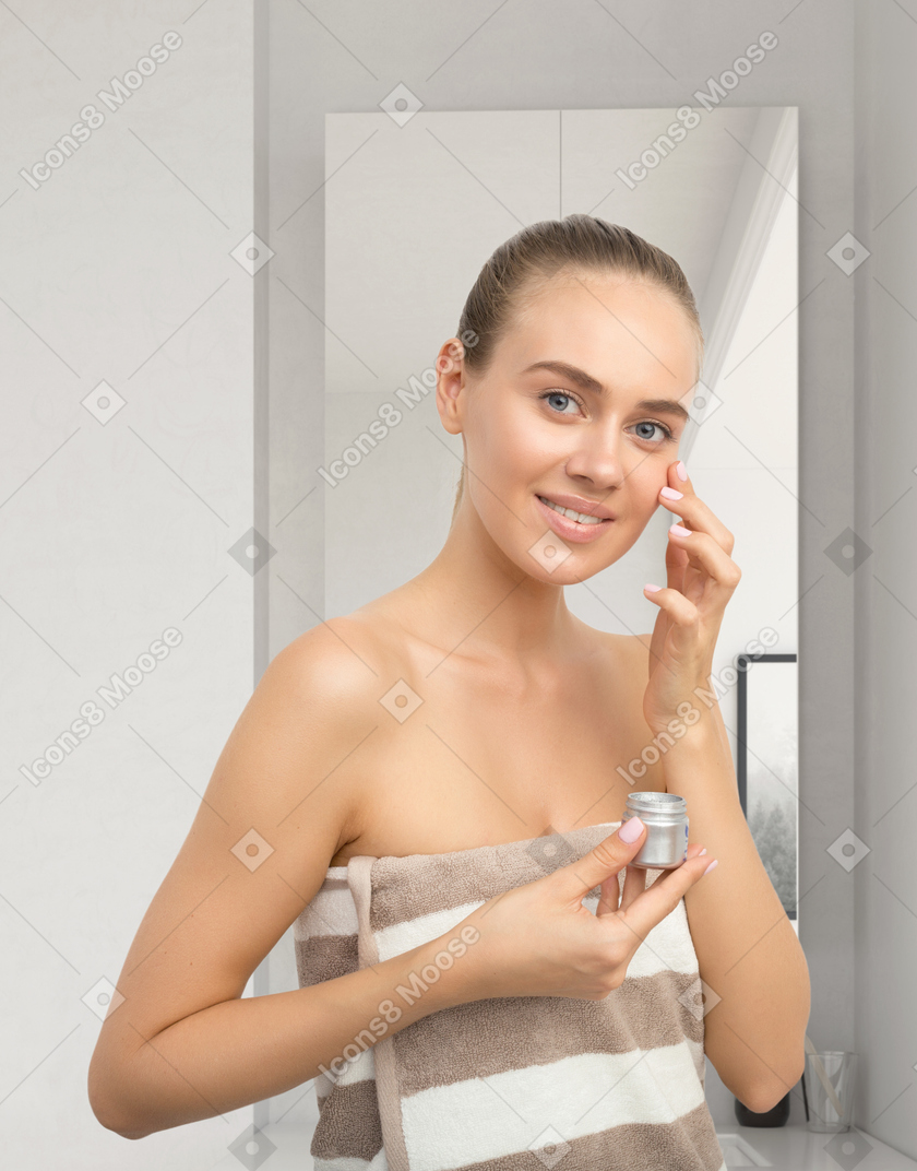 Beautiful young woman applying face cream