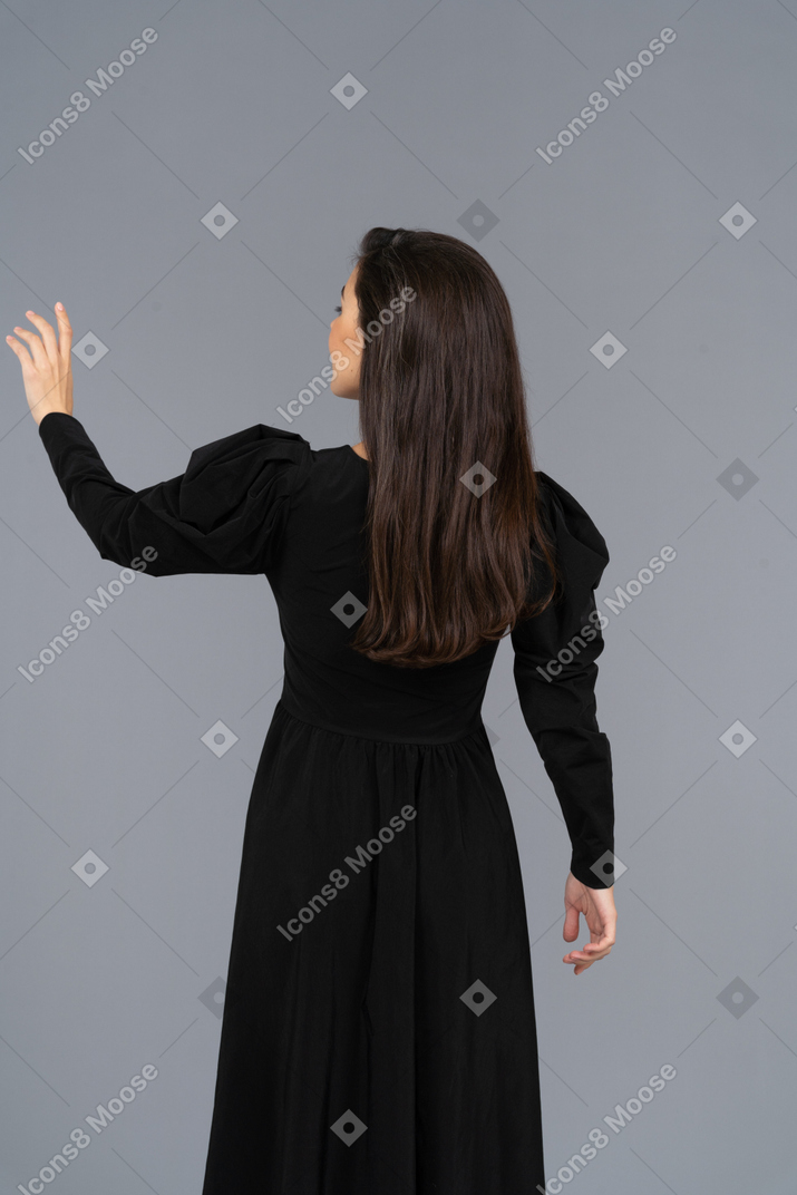 그녀의 손을 올리는 검은 드레스에 젊은 아가씨의 다시보기