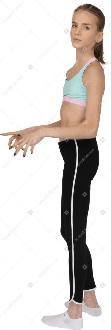 Vista lateral de uma adolescente em roupas esportivas estendendo os dedos e olhando para a câmera