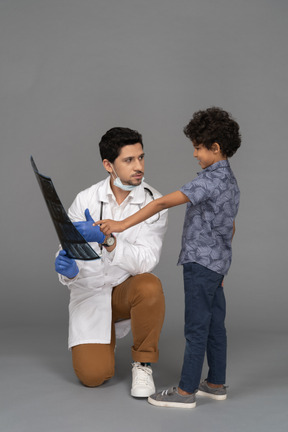 Médico mostrando foto de raio-x de menino