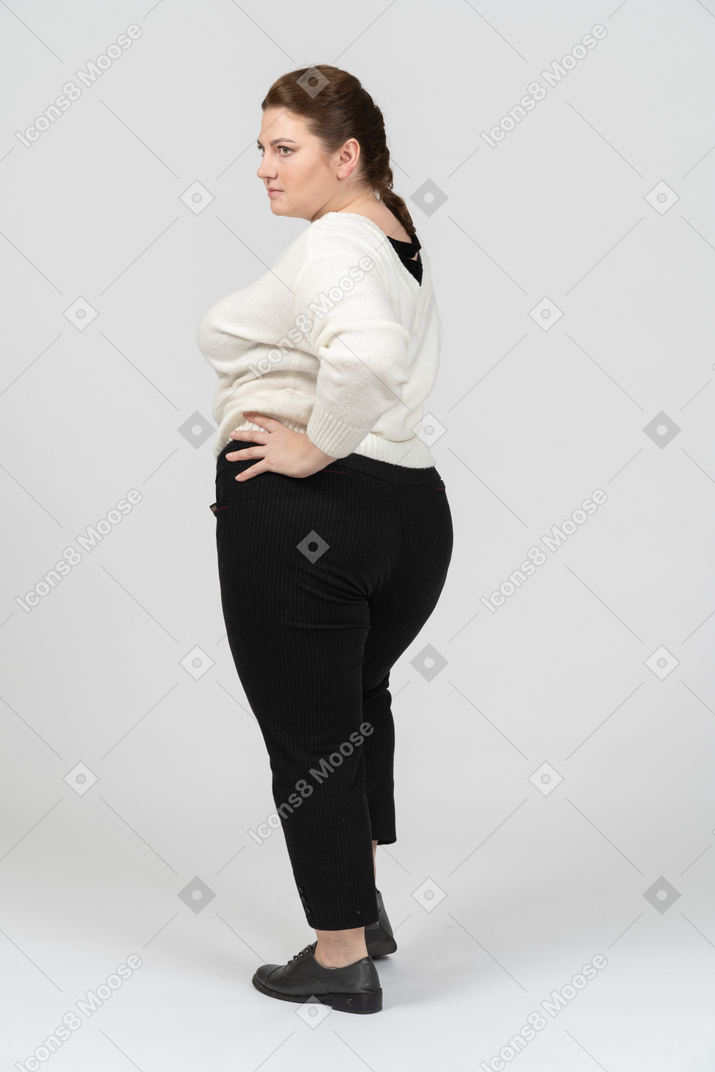 Donna grassoccia in maglione bianco in posa con le mani sui fianchi