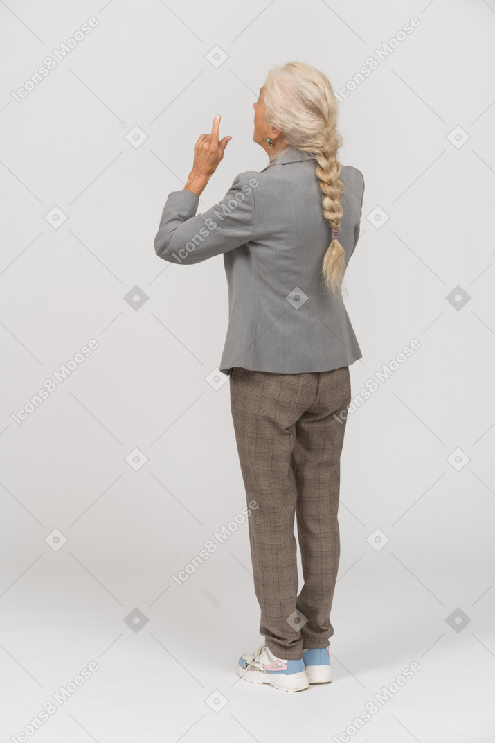 Vista posteriore di una vecchia signora in abito che indica con le dita