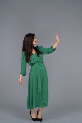 Vista di tre quarti di una giovane donna di saluto in abito verde