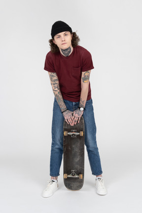 A teenager standing with his skateboard