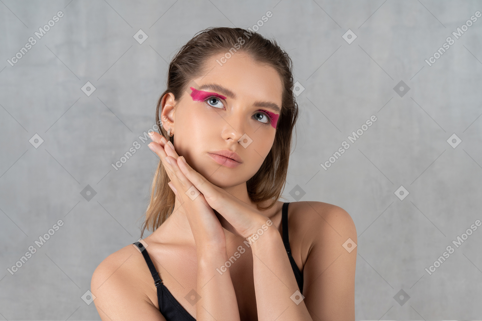 Portrait of a young woman with bright pink eye make-up daydreaming