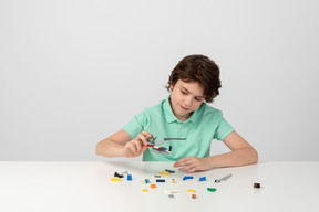 Мальчик в зеленой рубашке поло играет со строительными кубиками