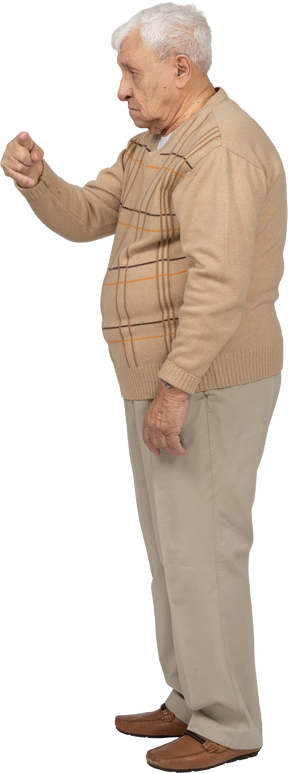 Vue latérale d'un vieil homme en vêtements décontractés pointant du doigt