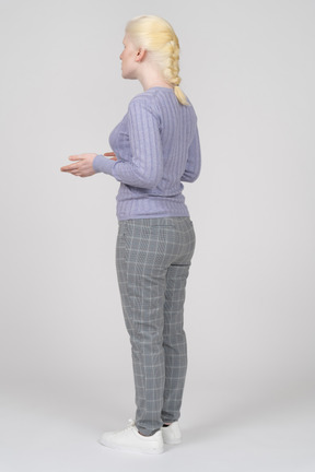 Three-quarter back view of a young blonde woman explaining something