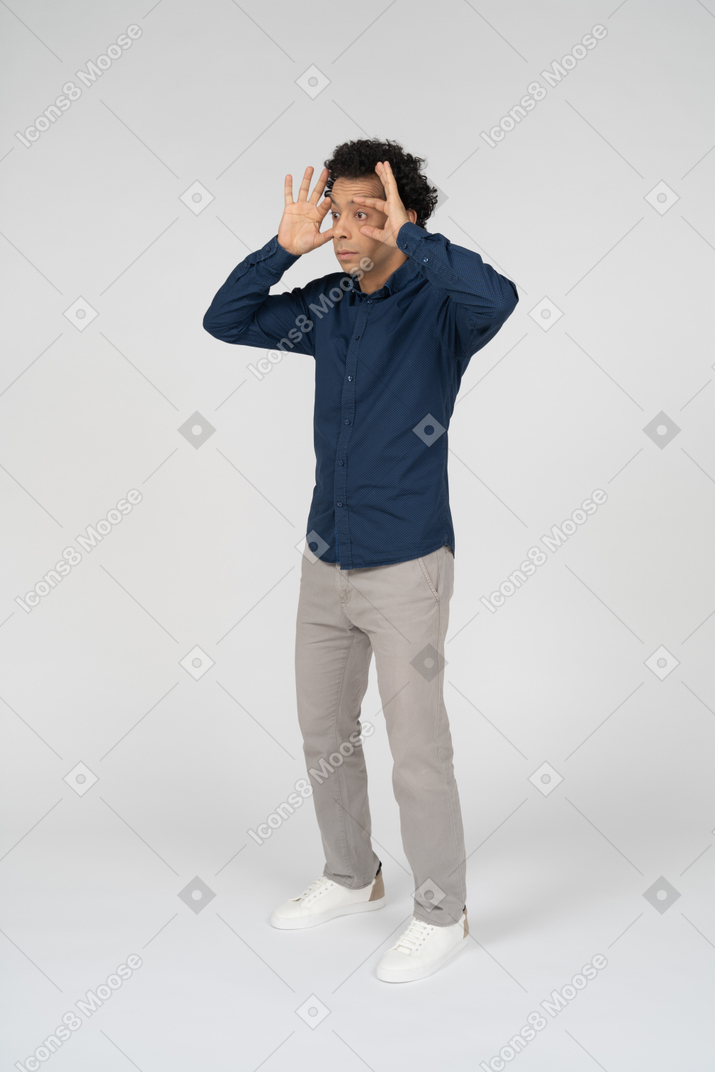 Front view of a man in casual clothes looking through imaginary binoculars