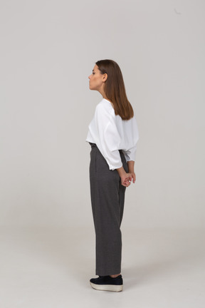 Vista posteriore di tre quarti di una giovane donna in abiti da ufficio che si tiene per mano dietro