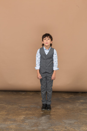 一个穿着西装的男孩站着不动的前视图