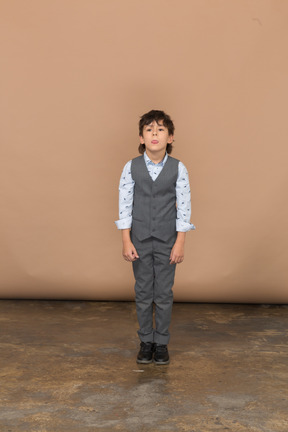 Vista frontal de un niño en traje parado quieto