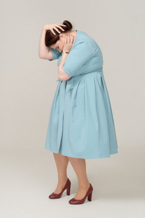 頭に触れる青いドレスの女性の側面図