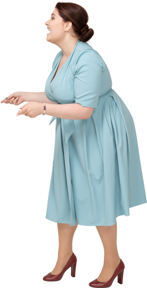 一个快乐的女人在蓝色连衣裙摆姿势的侧视图