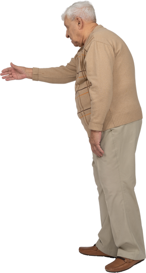 Seitenansicht eines alten mannes in freizeitkleidung, der eine hand zum schütteln gibt