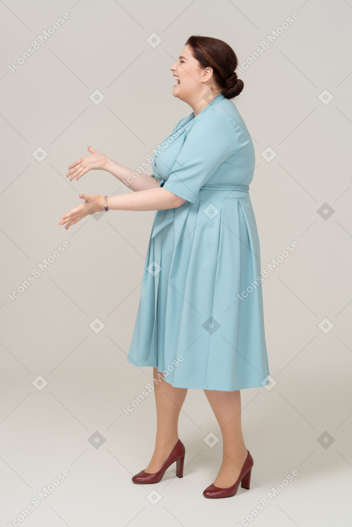 Mulher feliz em vestido azul posando de perfil
