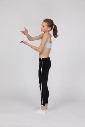 Side view of a teen girl in sportswear raising hand and arguing