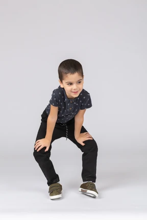 Front view of a cute boy squatting and looking at camera