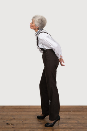 Vista lateral de una anciana sorprendida haciendo pucheros inclinándose hacia adelante