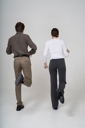 Back view of a young couple in office clothing raising leg
