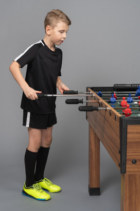 Side view of a boy playing foosball