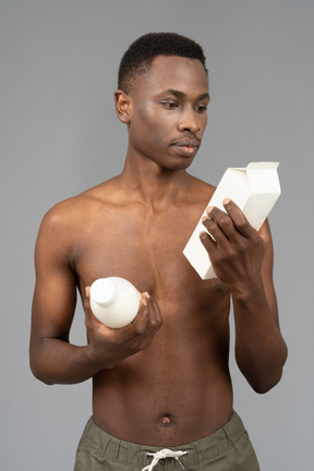 A shirtless young man holding milk