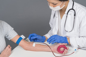 Doctora tomando sangre de la vena del paciente