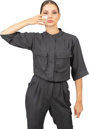 Front view of a young woman in a jumpsuit removing make-up