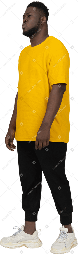 Three-quarter view of a thoughtful young dark-skinned man in yellow t-shirt